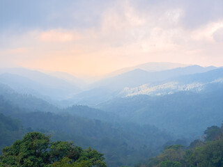 Sunshine illuminates a beautiful mountain surrounded by the mist of the rain forest in Thailand.