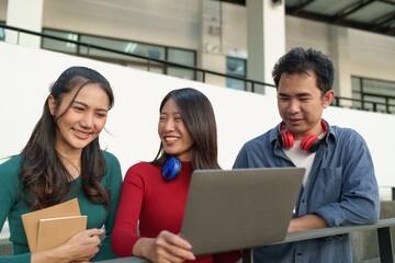 Group of Asian university students with headphones studying outdoor learning Make data reports from laptop learning and education concept Concepts of teenagers and people in the online world.