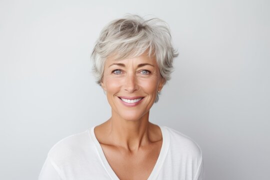 Closeup portrait of a happy senior woman looking at camera against grey background