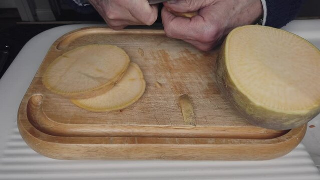 Peeling slices of swede before chopping to make a handmade root vegetable soup