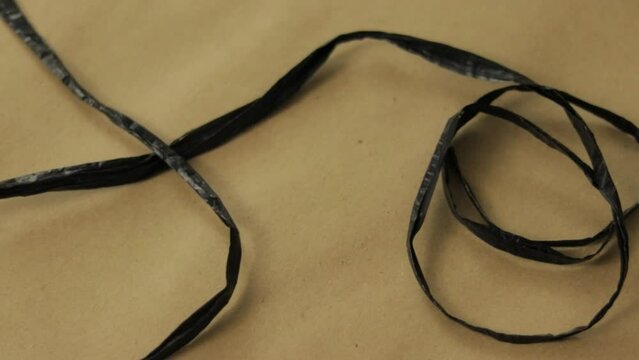 Thin strip of black raffia delicately arranged on textured craft paper