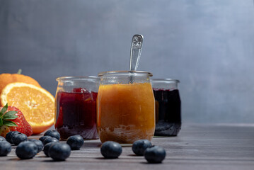 Homemade orange marmalade, assortment of homemade jams in glass jars. Front view, seasonal fruit...