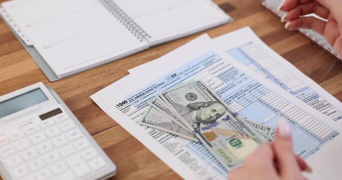 Tax bill in American dollars, calculator with pen and US money in female hands