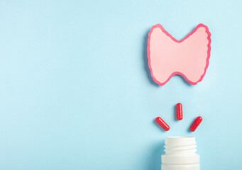 Thyroid gland decorative model with pills on pastel blue background. Hyperthyroidism,...