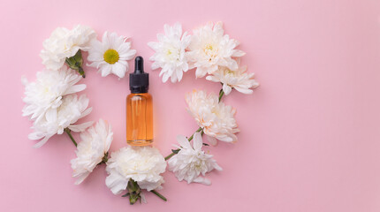Flat lay flowers and pipette bottle with oil on pink background with copy space. Organic aroma...