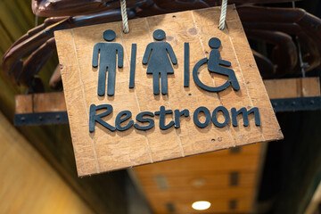 Ceiling wooden restroom or toilet direction sign with gentleman, lady and disability person icon....