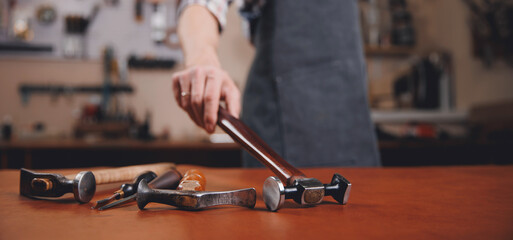 Artisan cobbler hold tools for leather textile in workshop. Concept banner background tailor shoes maker
