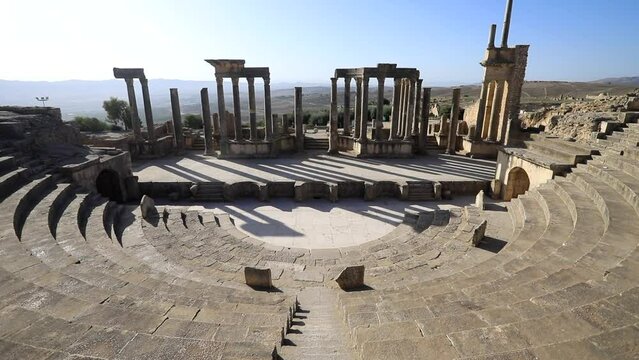 Ancient Roman theater of Dougga with arches and steps under clear blue sky