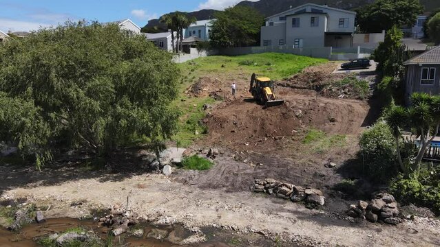 Yellow digger clearing a steep piece of land by pushing soil down the hill