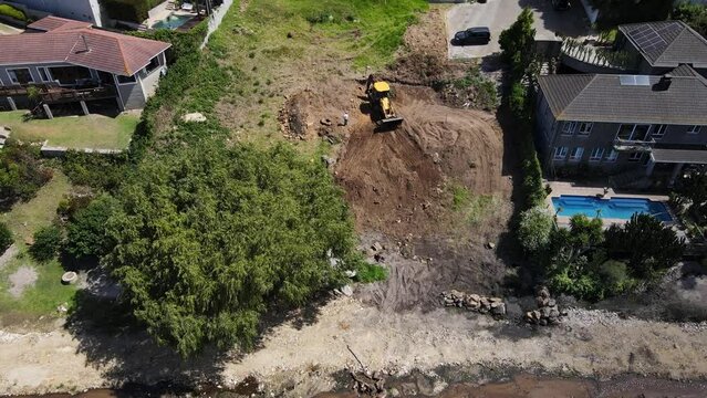 Excavator digger working on a plot and moving soil around as seen from above