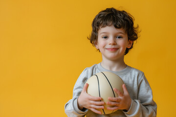 Sports and little boy athlete holding volleyball ball on yellow background, Exercise and childhood...