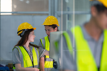 Portrait of young male factory worker wearing a hard hat looking at a computer screen used to control production.