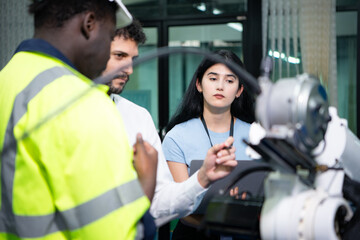 Fototapeta na wymiar Technicians are introducing industrial hand robots to businessperson of factory industry who will use them in large-scale complex manufacturing operations.