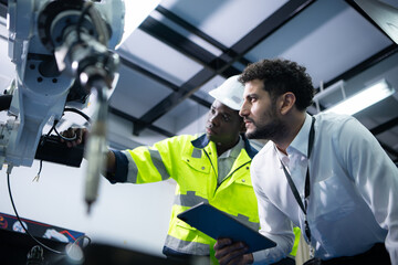 Technicians are introducing industrial hand robots to businessperson of factory industry who will...