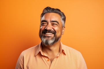 Handsome man with beard and mustache smiling over orange background.