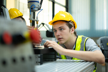 Portrait of a technician young male worker in a factory working on a small robot machine