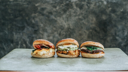 Landscape of three burgers on a plate, each with different toppings and buns