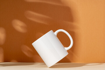 White ceramic mug on peach background with shadows