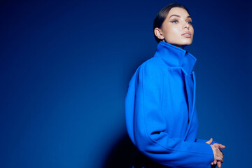 fashion portrait of young elegant woman in blue coat on blue background