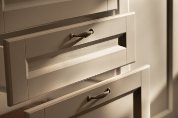 Extended drawers of a beige chest of drawers with bronze handles in a retro style close-up with...