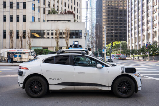 San Francisco, CA, USA - Feb 22, 2024: A Waymo all-electric robotaxi stops at a red light on the streets in the Financial District of San Francisco. Waymo One is an autonomous ride-hailing service.