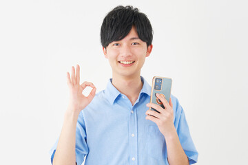 スマートフォンを持ってOKサインをする男性　白背景