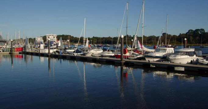 multiple sailing dinghies sailing past moored up motor yachts and out of frame on Lymington river