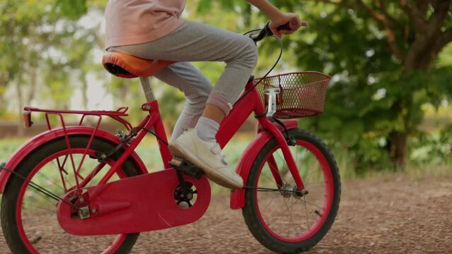 picture of a red bicycle with small kid girl legs. wearing white sports shoes. she Learning to ride a two-wheeled bicycle in the park. In different perspectives. isolated green garden background