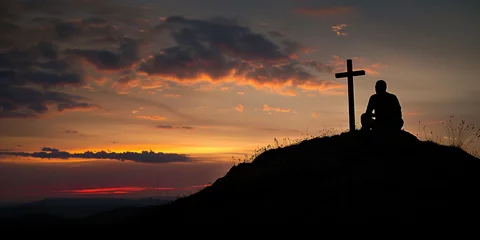 Schilderijen op glas Regretting sins, missing people who passed away, deeply religious person, praying, thinking about soul and meaning of life. Silhouette of a man sitting on high hill with cross during sunrise or sunset © Valeriia