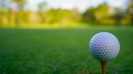 Golf ball on green grass in the evening golf course with sunshine background.