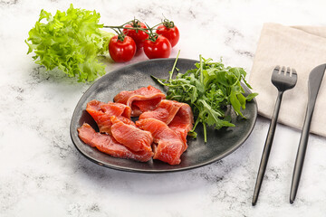 Sliced salmon with fresh arugula