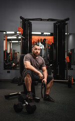 A large bearded man in the gym performs a squat exercise with a barbell. Preparation of a...