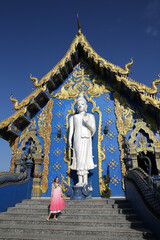 Tourist woman, fashion girl and Wat Rong Suea Ten, Blue Temple in Chiang Rai city, Thailand. Religious traditional national Thai architecture. Landmark, architectural monument. Buddhist temple, sight - obrazy, fototapety, plakaty