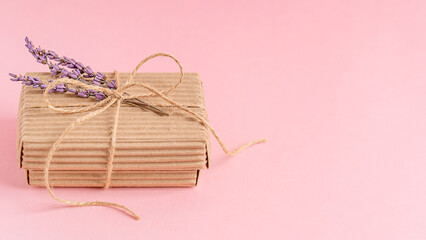 Craft carton disposable gift box tied with string decorated with dried purple lavender flowers on pink background with copy space used as eco friendly zero waste holiday packing for present decoration