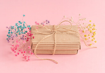 Craft carton disposable handmade gift box tied up with string decorated with dried colourful gypsophila flowers on pink background used as eco friendly zero waste holiday wrapping for greeting