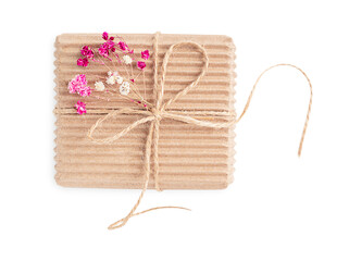 Top view of single craft carton disposable gift box tied with string decorated with dried red and pink gypsophila flowers isolated on white background used for greeting on holidays celebration