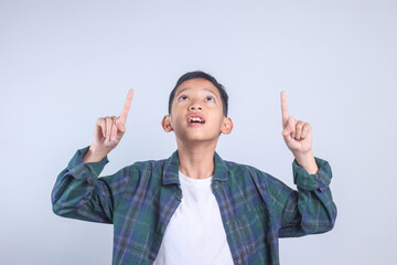 Little Asian boy pointing up showing copy space for advertisement. 