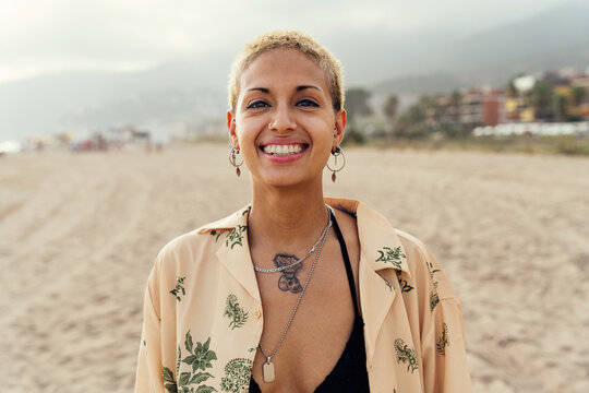 Portrait of beautiful young smiling woman at the beach at sunset