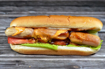 chicken hot dog with thousand island dressing sauce of ketchup mayonnaise, grilled chicken sausage, tomato, lettuce, called wiener (Vienna sausage), frankfurter frank, in a partially sliced hotdog bun