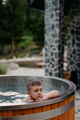 Little boy relaxing with eyes closed in hot tub. Summer holiday, vacation concept.