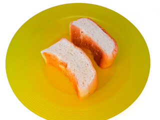 two slices of bread on a yellow plastic plate, isolated on a white background, concept of hunger, poverty and inflation impacting society or humans.