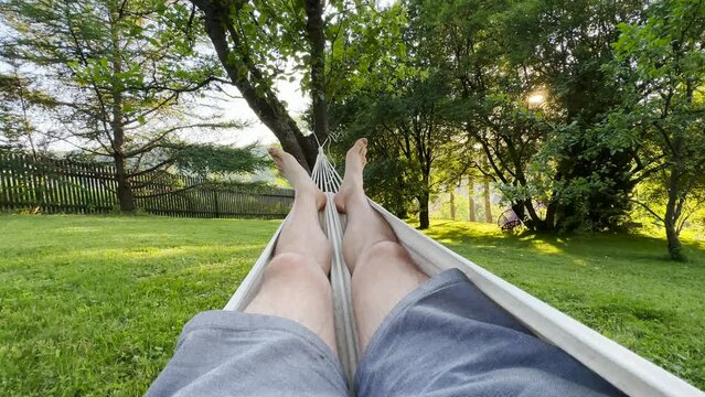 POV shot of a man relaxing in hammock in the garden