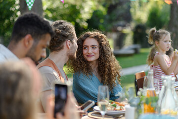 Portrait of couple sitting at the table with family and friends at the family garden party.