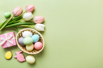 Easter frame with eggs, gift box and tulip on a colored background. The minimal concept. Top view Happy Easter composition. Card with a copy space of the place for the text