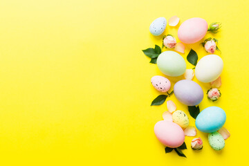 Happy Easter. Easter eggs on colored table with yellow roses. Natural dyed colorful eggs background top view with copy space