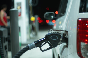 Economy car at gas station being filled up with regular gasoline fuel at night. Closeup, shallow DOF. - 745634275