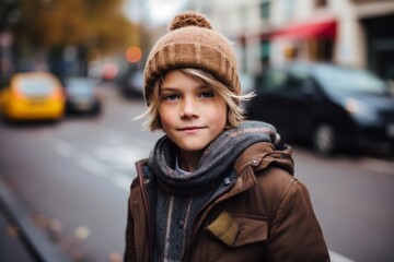Portrait of a cute little boy in a brown coat and hat on the street