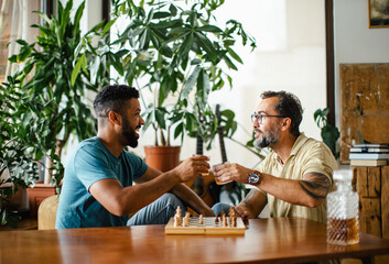 Best friends playing chess together, drinking whiskey and talking. Concept of male friendship,...