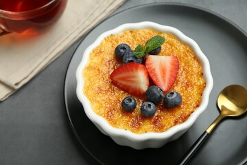 Delicious creme brulee with berries and mint in bowl on grey table, closeup
