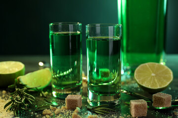 Absinthe in shot glasses, brown sugar, lime and rosemary on table, closeup. Alcoholic drink